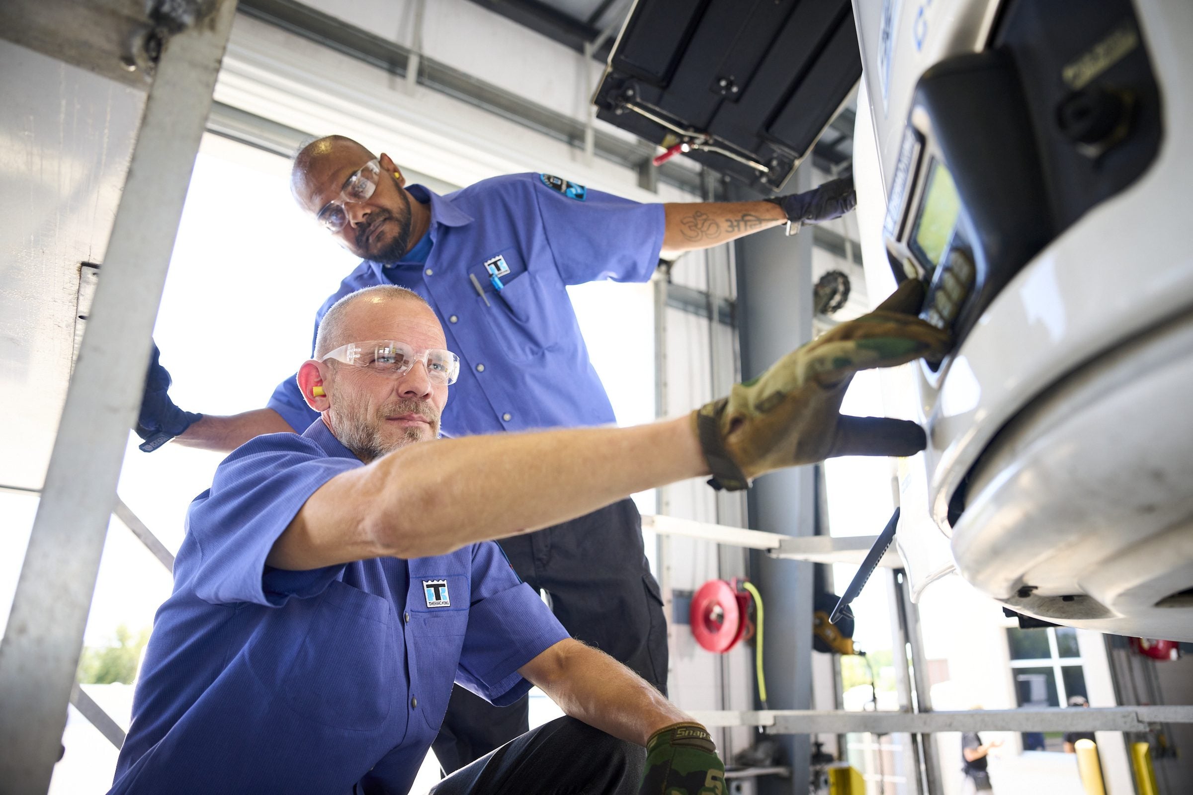 Two technicians inspecting a Thermo King unit