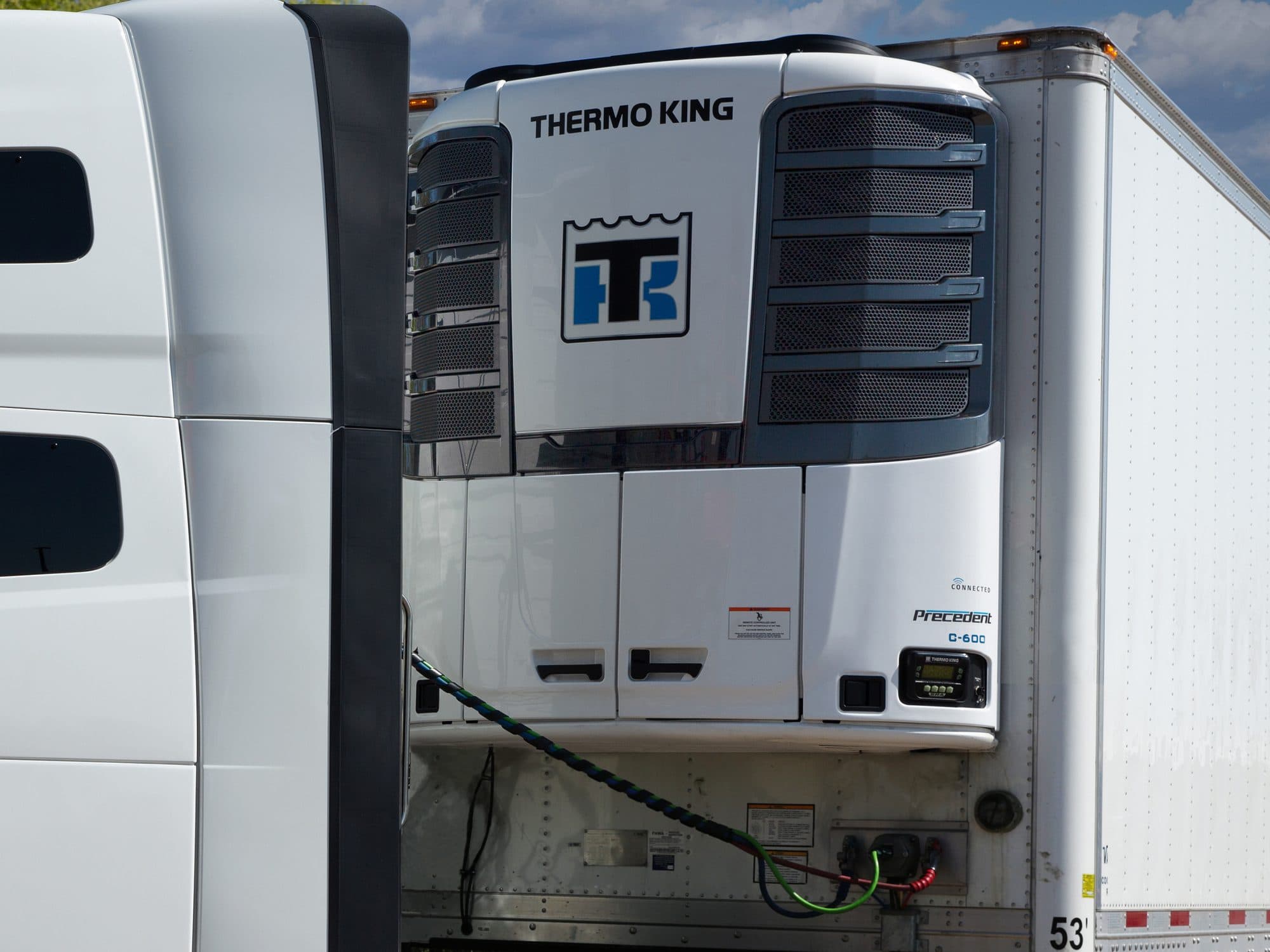 A Thermo King Precedent C-600 on the nose of a white trailer, behind a tractor's sleeper cab