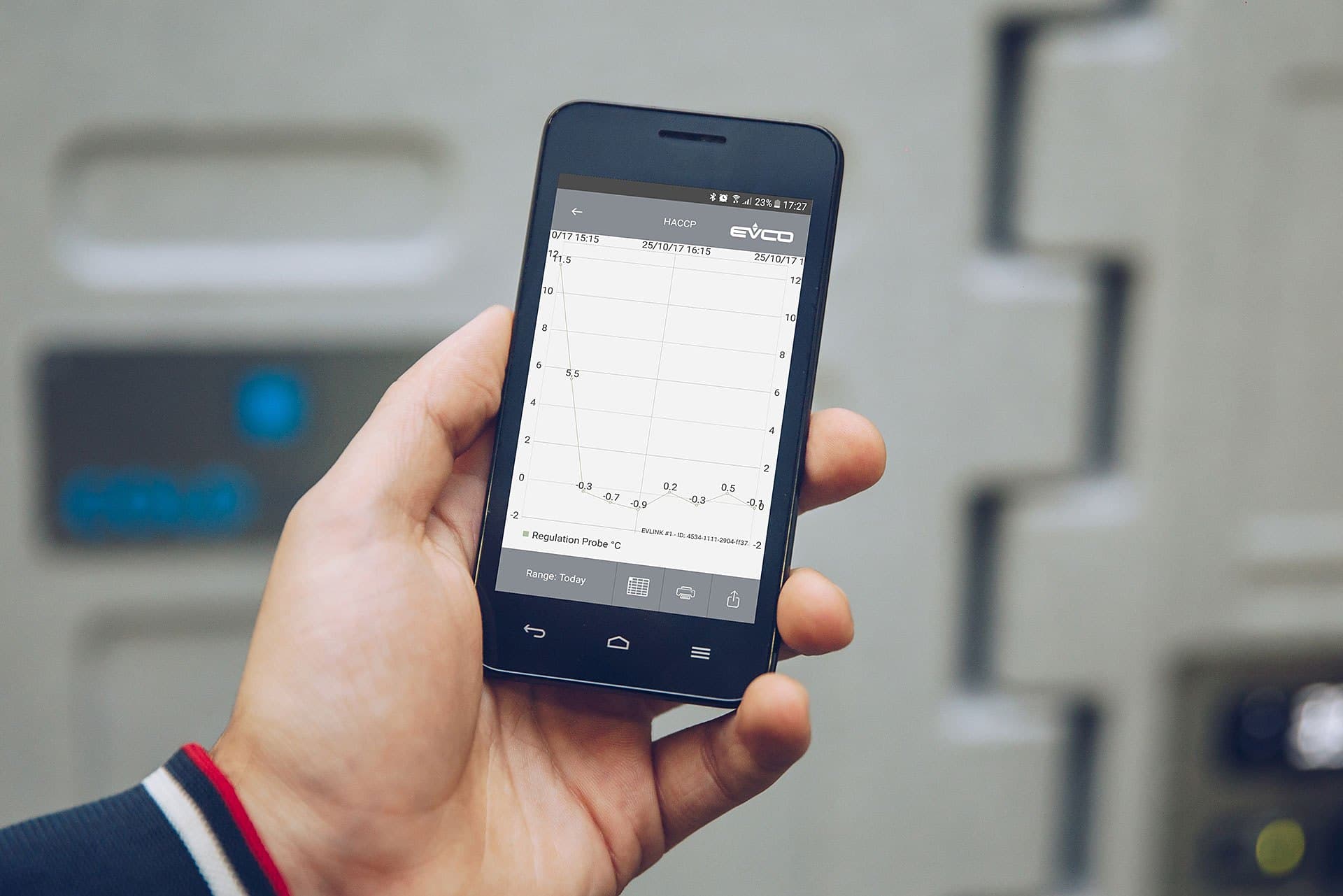 A hand holding a phone showing a temperature graph from a Coldtainer