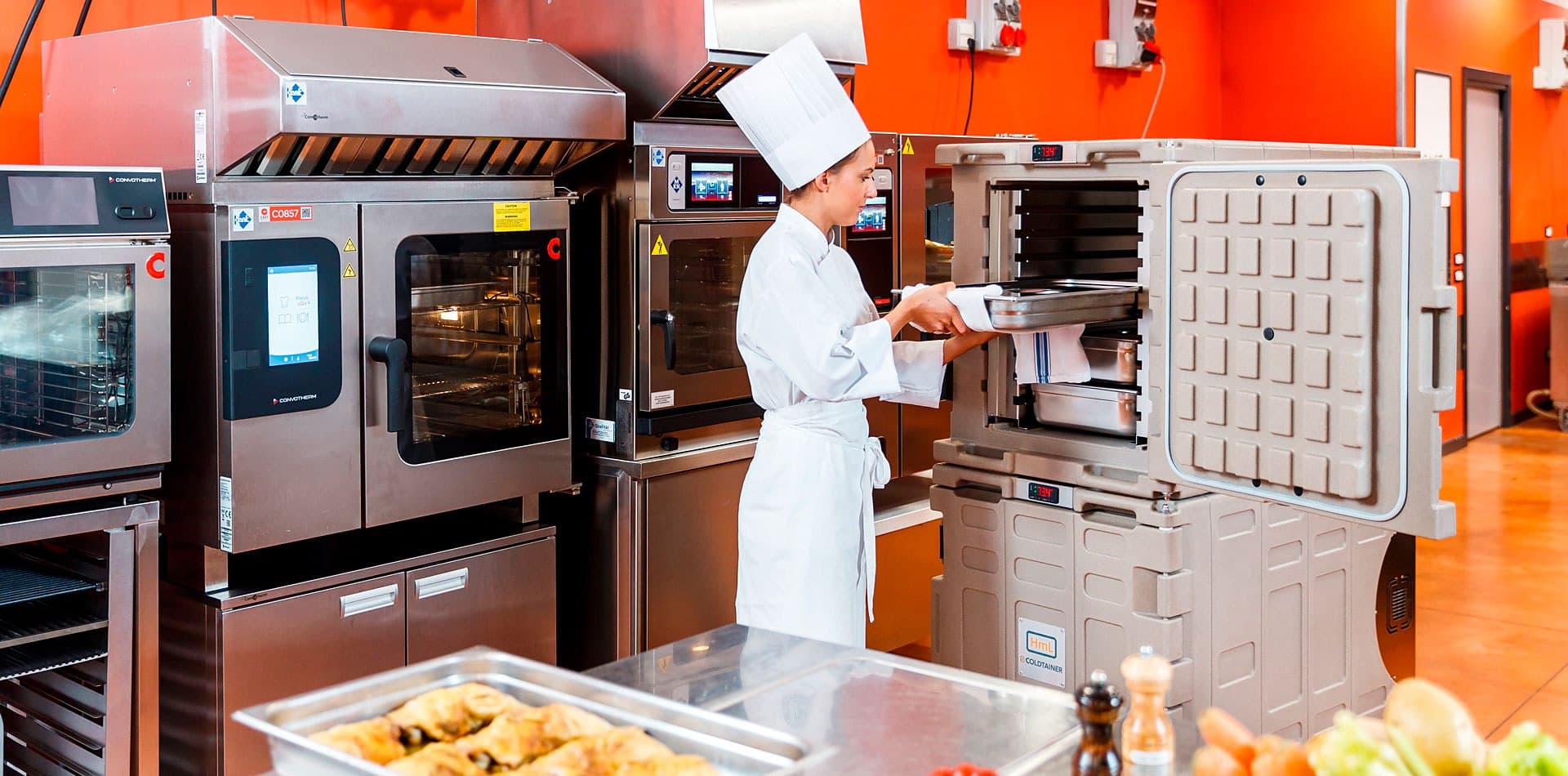 A chef sliding a tray of hot food into a Coldtainer H140 hot food container in a commercial kitchen