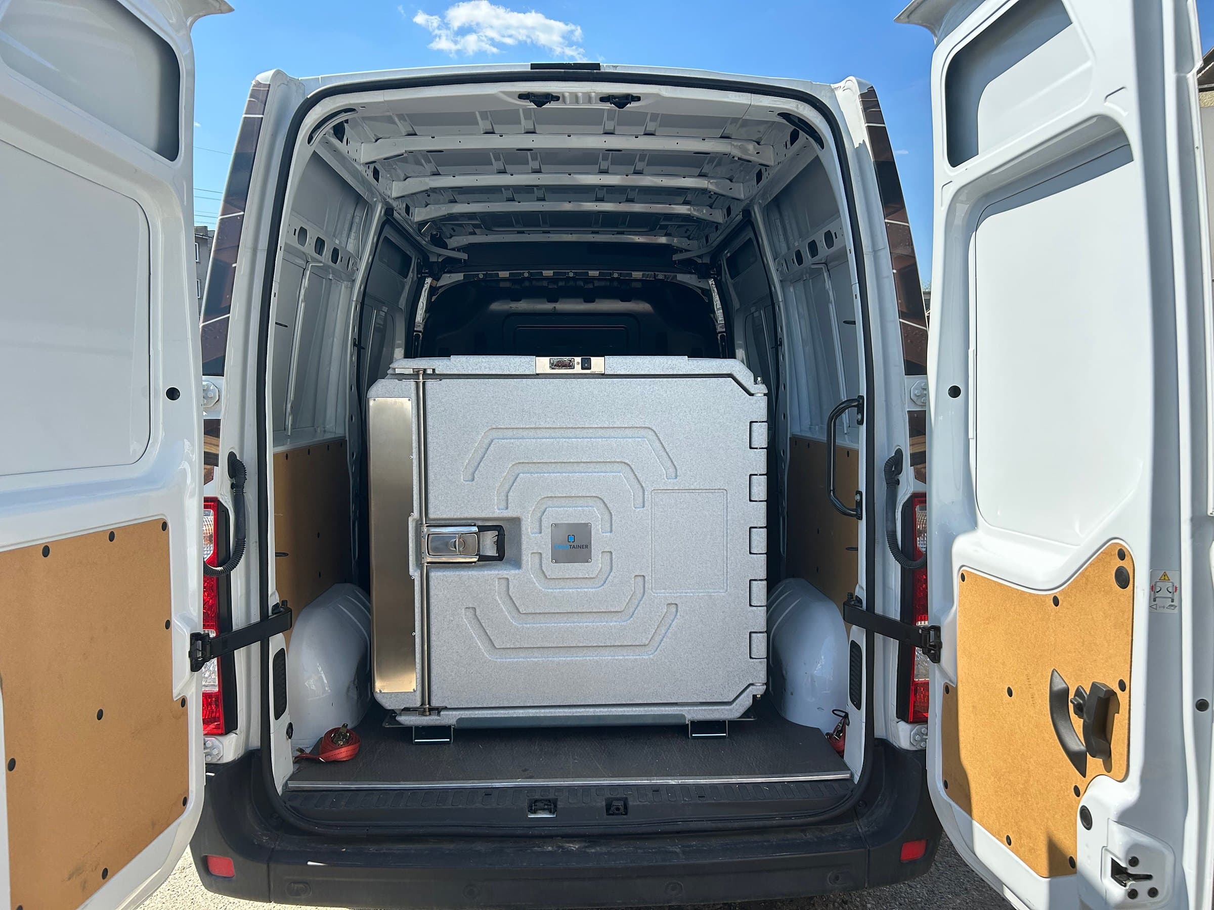 A Coldtainer F1020 AuO strapped in the back of an empty cargo van, rear doors open