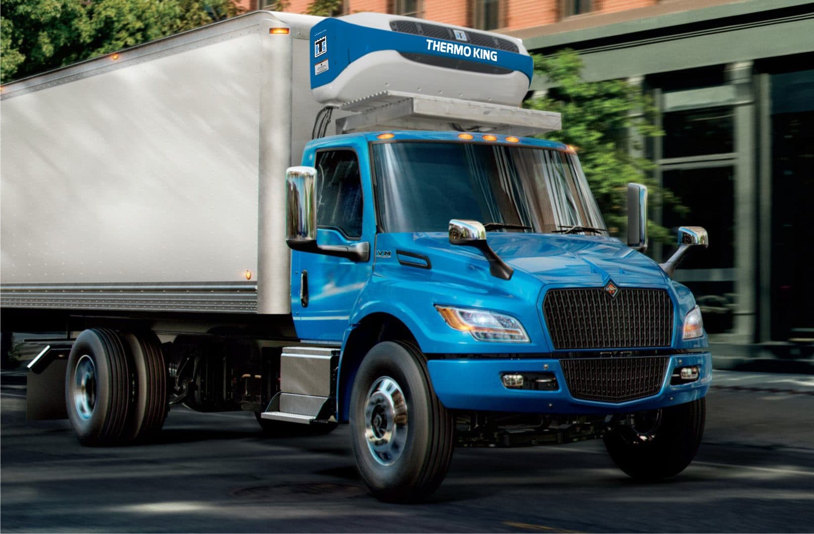 A Thermo King e1000 on a blue electric box truck, driving past trees