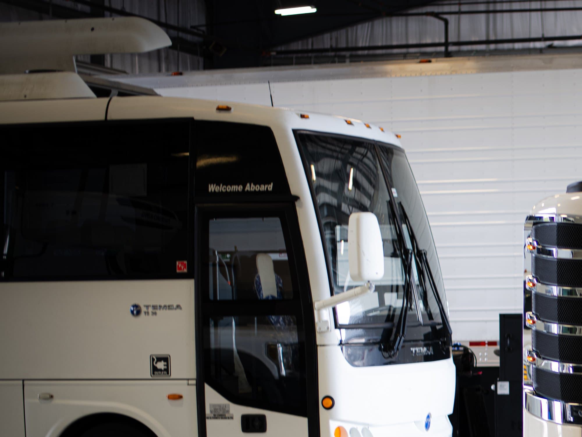A coach bus parked in a TKSE service bay, its rooftop unit in view