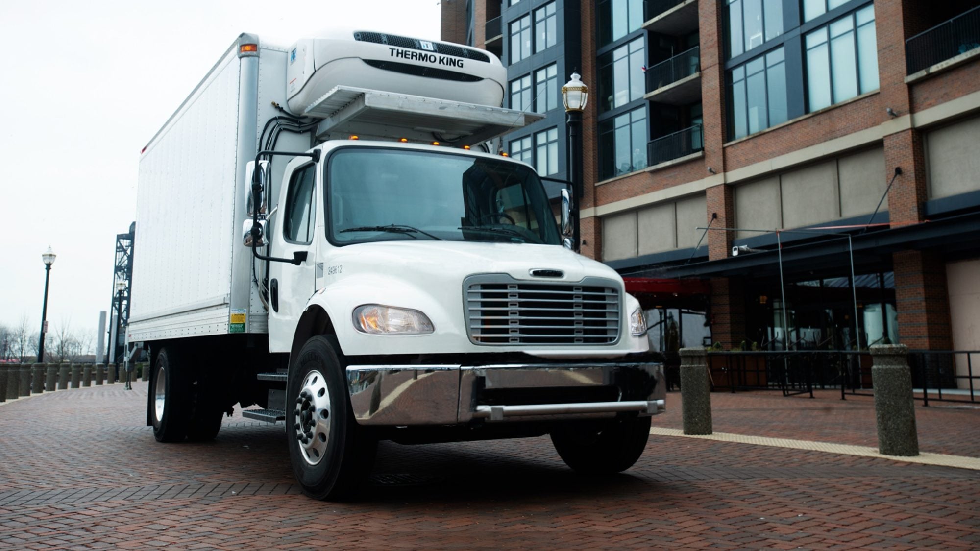 A white box truck with a Thermo King T-90 Series unit above the cab, on a brick plaza