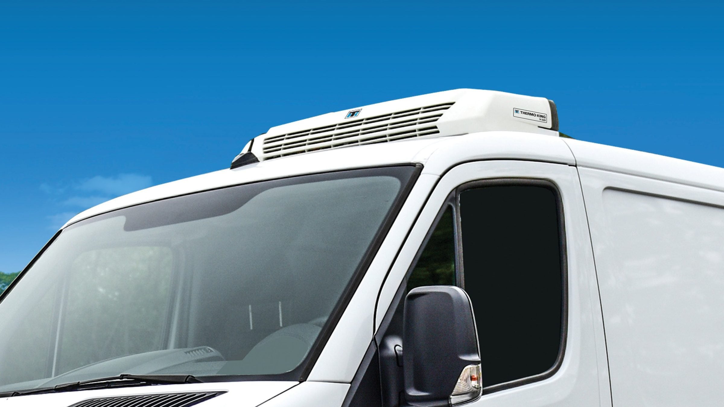 A white high-roof van with a Thermo King V-Series rooftop unit, against a blue sky