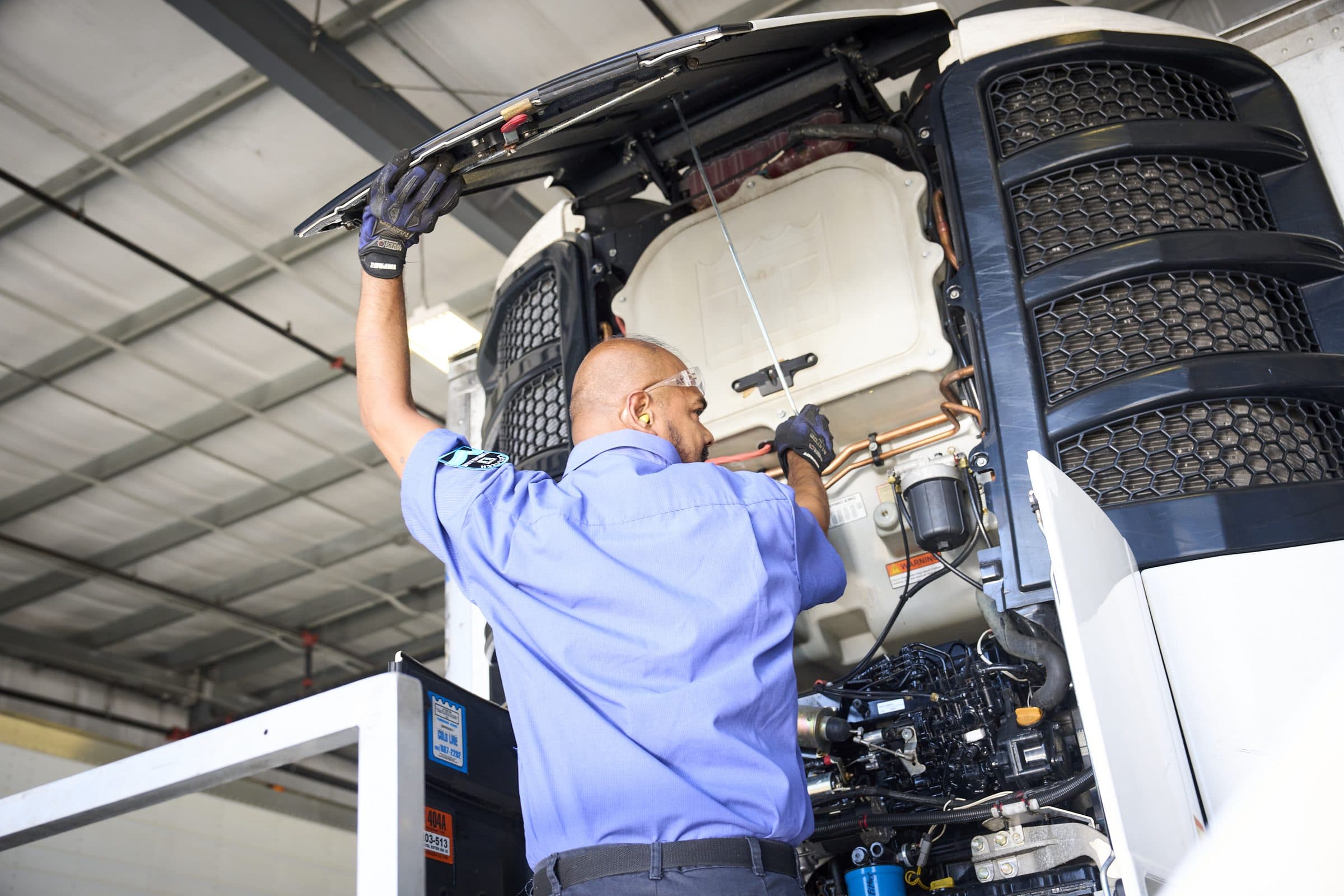 A technician working inside an opened-up Thermo King Precedent trailer unit