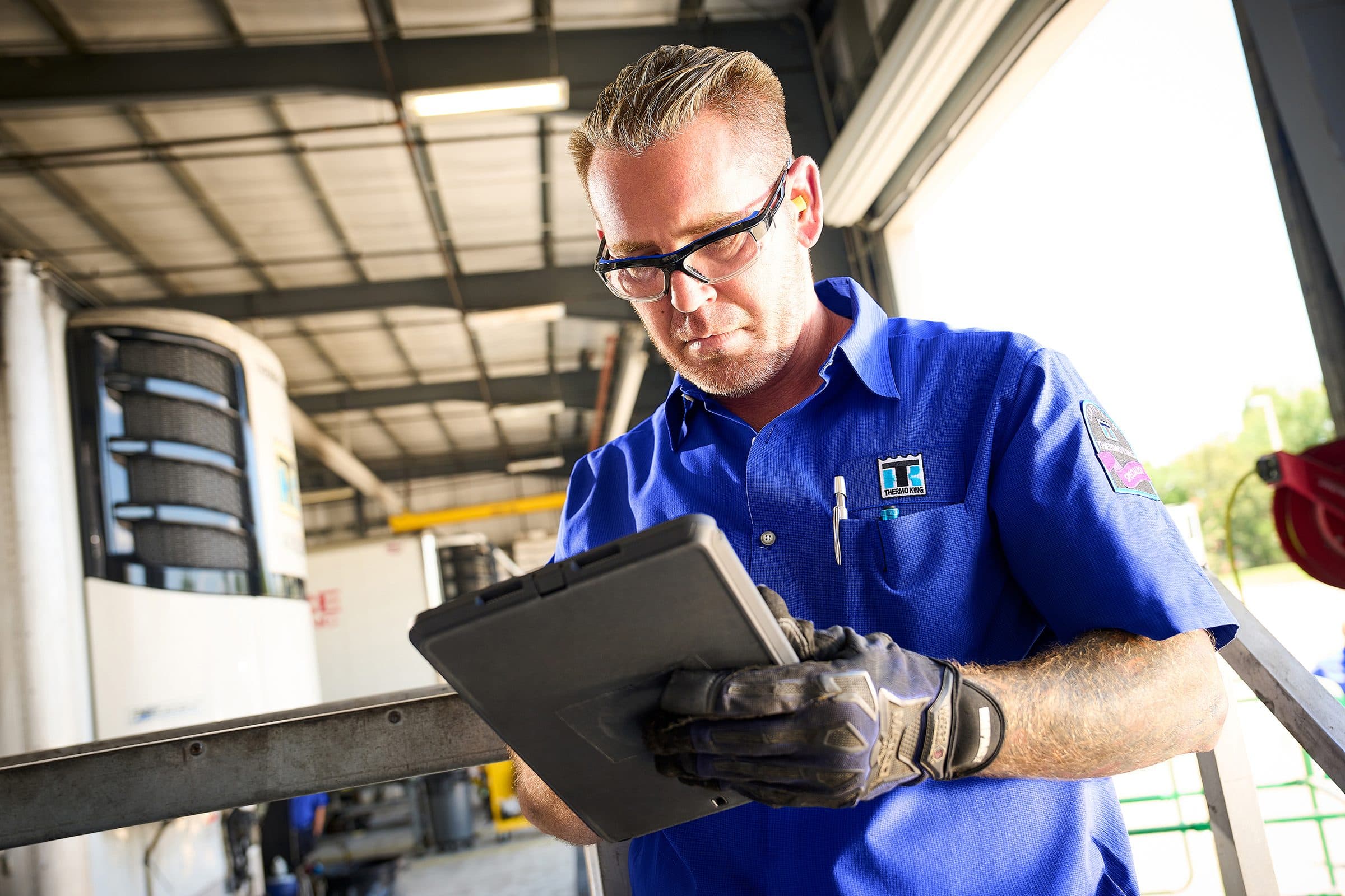 A technician entering notes on a tablet beside a trailer