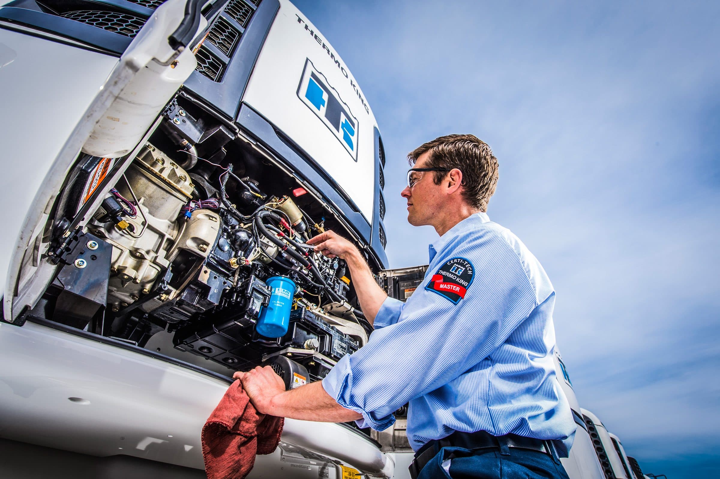 A technician working on an opened-up Thermo King Precedent trailer unit